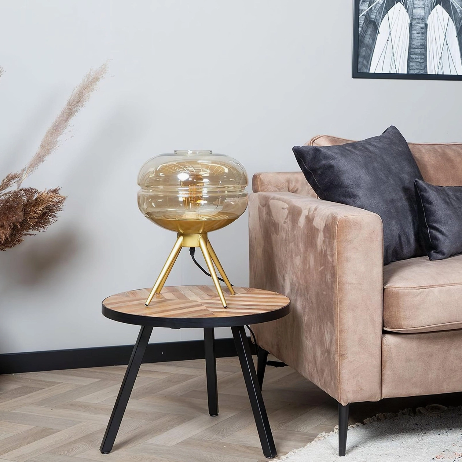 Compact amber tiered glass table lamp on black-legged side table in modern residential living room