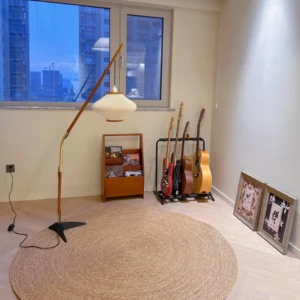 Arc floor lamp in modern living room with jute rug and wooden furniture, side eye-level perspective showing warm ambient lighting