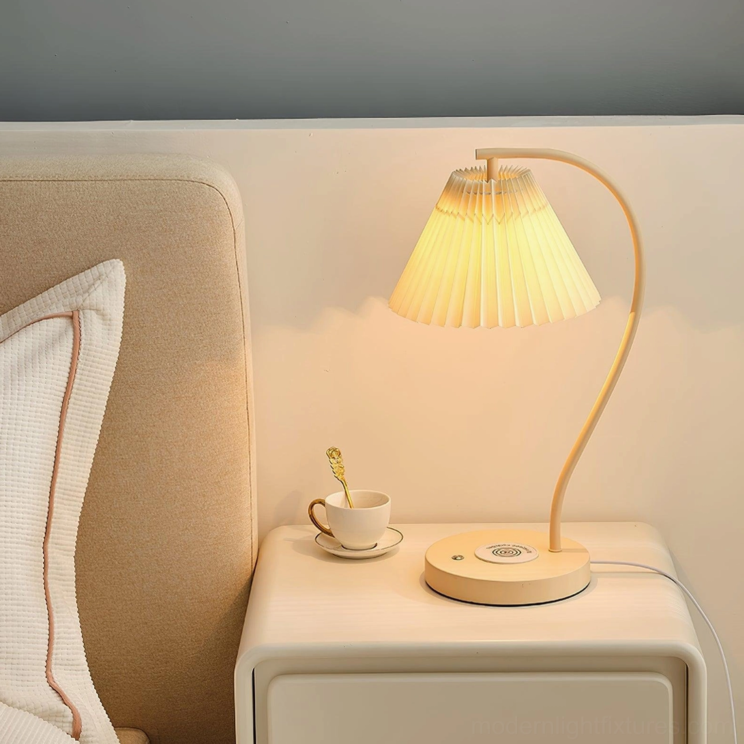 Modern pleated bedside lamp with warm glowing fabric shade in neutral bedroom