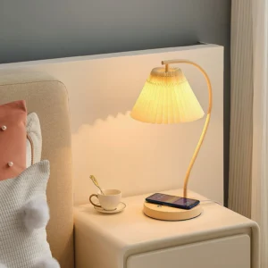Contemporary pleated bedside lamp emitting warm light on bedroom nightstand