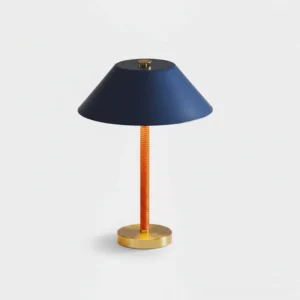 Modern blue volume table lamp with navy blue conical shade and warm amber ribbed metal stem on white background