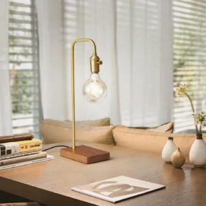 Vintage brass desk lamp displayed on living room coffee table with books and decorative vases, three-quarter view