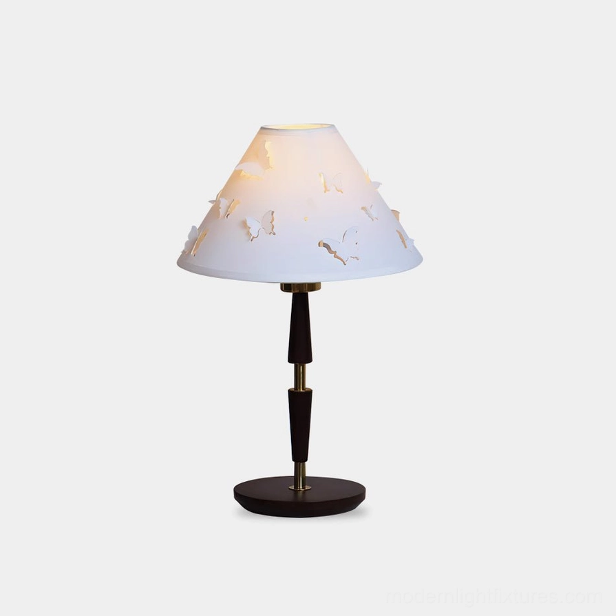 Modern butterfly perforated table lamp with hollow fabric shade on white background studio photography