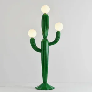 Designer cactus-shaped floor lamp displaying green vertical ribbed texture and three illuminated globe lights against neutral wall background