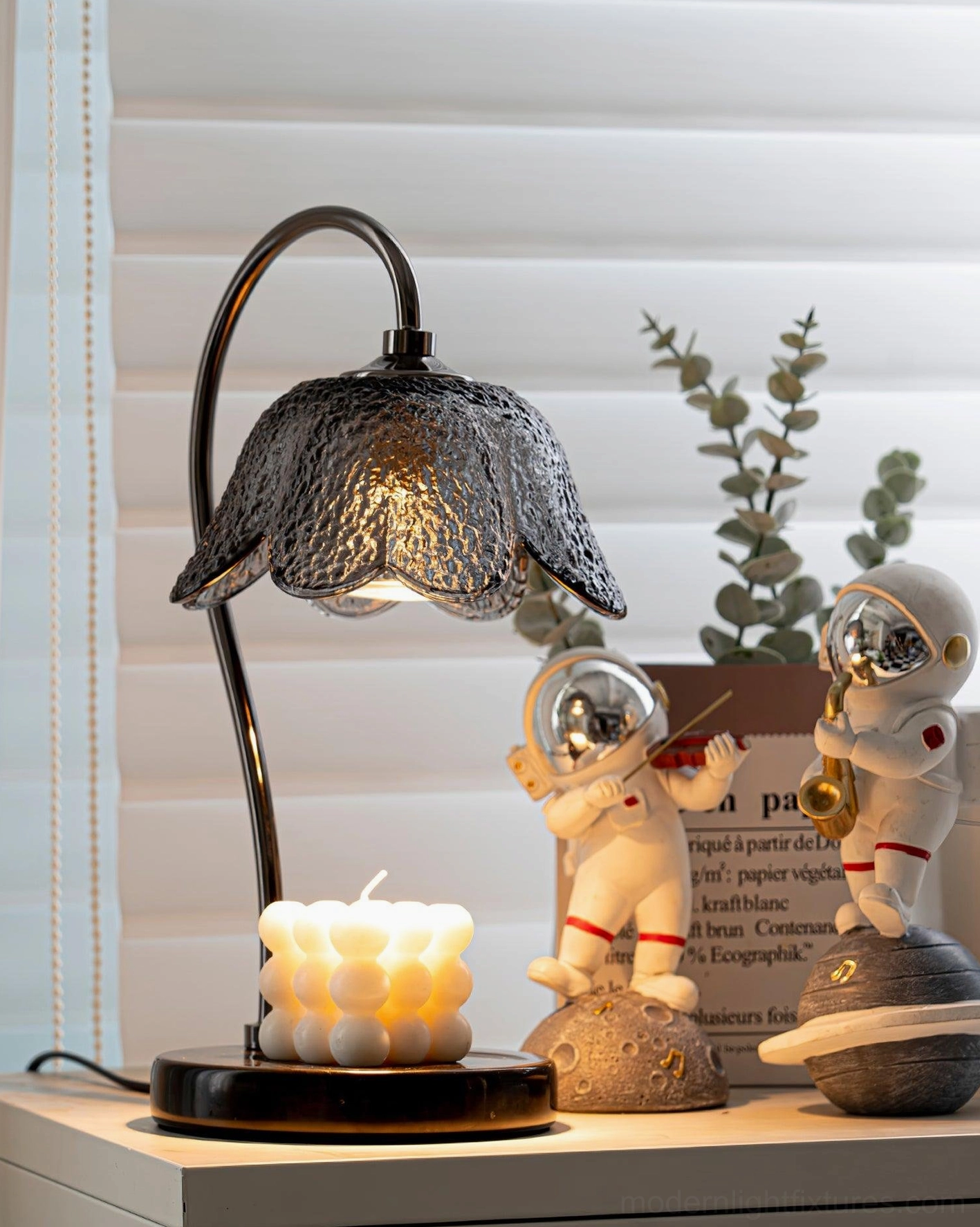 Decorative candle warmer lamp on shelf with candle and astronaut ornaments for modern home decor