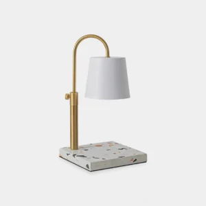Modern candle warmer table lamp with white fabric shade and brass gold arched arm on terrazzo base front view