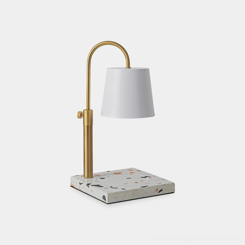 Modern candle warmer table lamp with white fabric shade and brass gold arched arm on terrazzo base front view