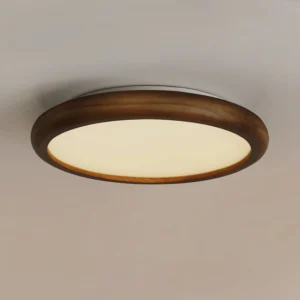 Modern flush mount ceiling lamp illuminated in residential interior, upward angle showing warm glow and wood frame detail