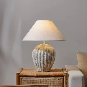 Contemporary ceramic table lamp with weathered grey base displayed on rattan side table in living room setting