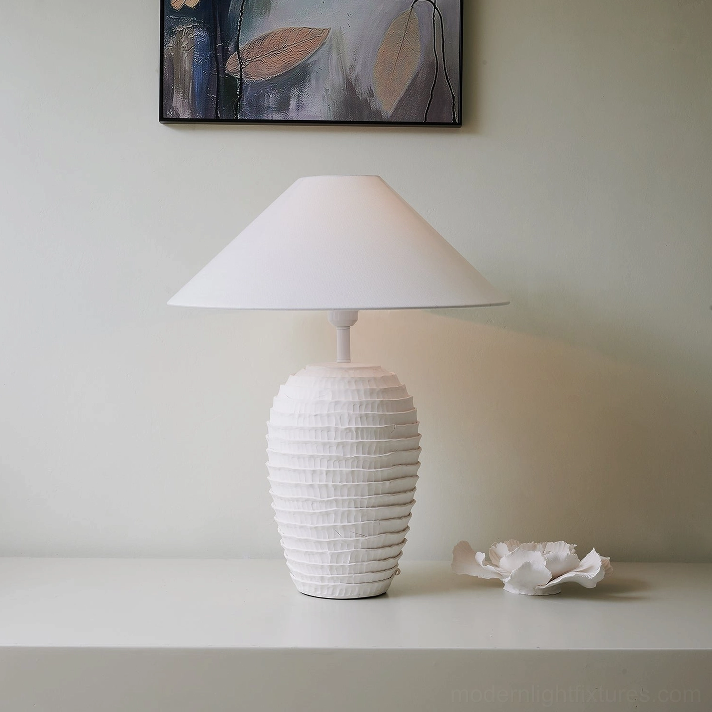 White sculptural ceramic table lamp in contemporary interior setting with ceramic floral decoration