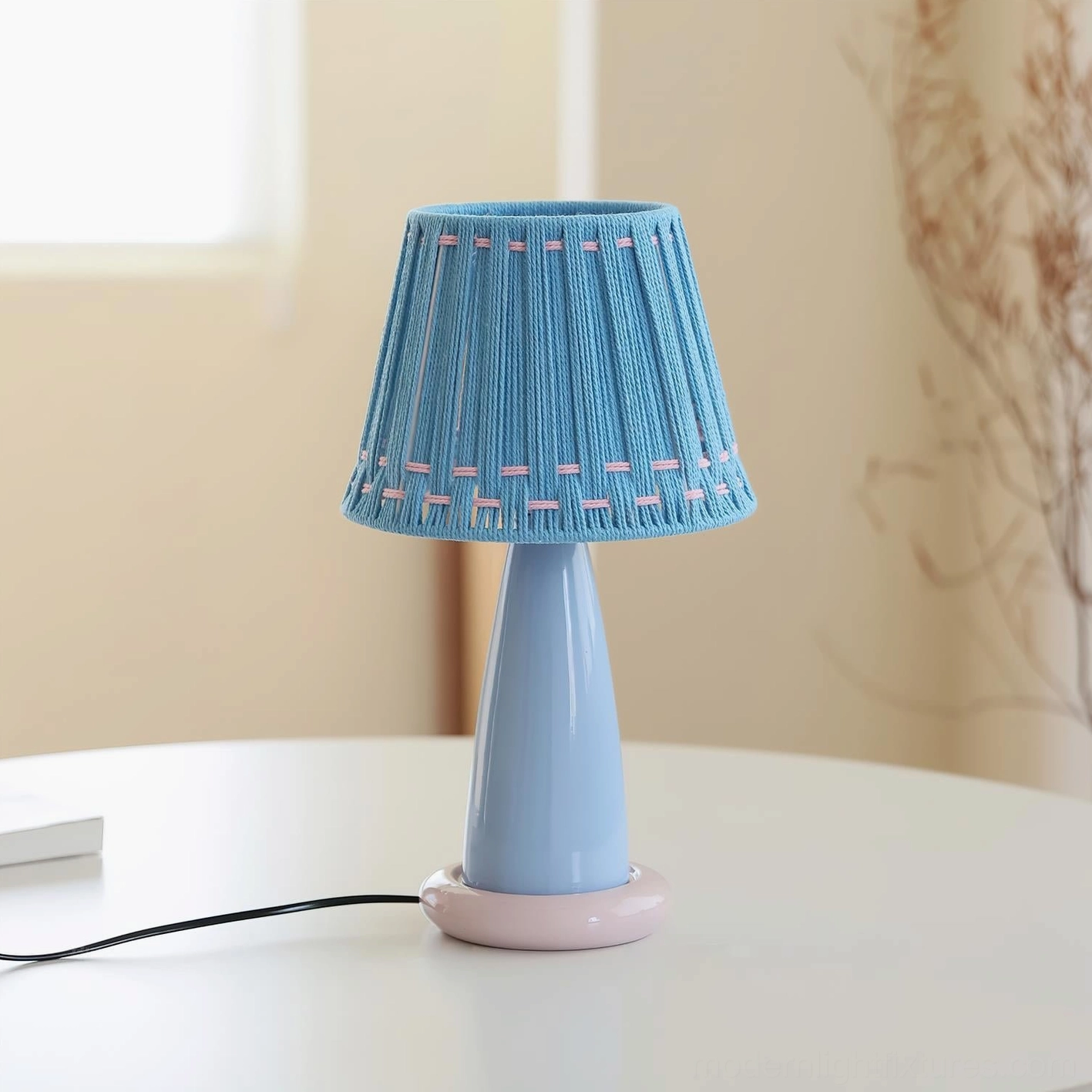 Contemporary ceramic table lamp styled on white side table, featuring handcrafted ceramic base and fabric woven shade in soft pastel colors