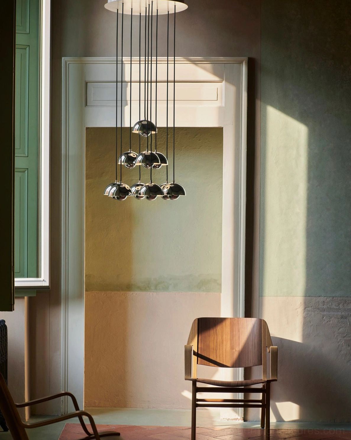 Polished chrome dome pendant chandelier hanging in modern residential entryway hallway with warm ambient lighting and contemporary home decor