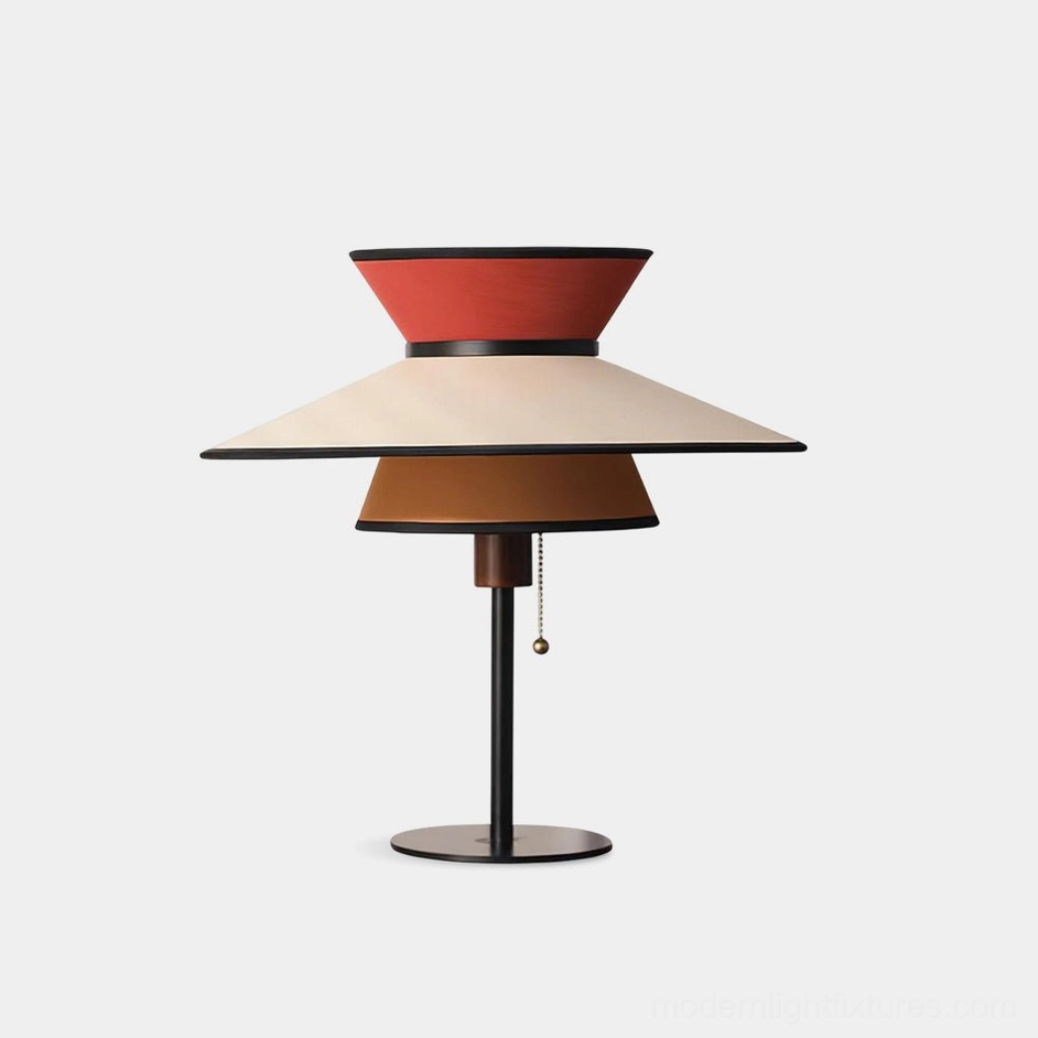 Modern conical table lamp with three-tiered layered fabric shades in warm earthy tones and orange-red accents, featuring sleek black metal stem on white studio background