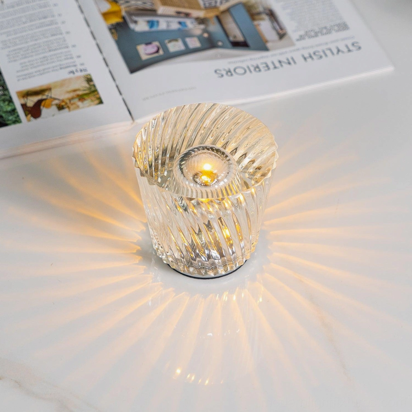 Modern cordless crystal diamond table lamp on display surface, geometric faceted design, minimalist aesthetic, portable lighting