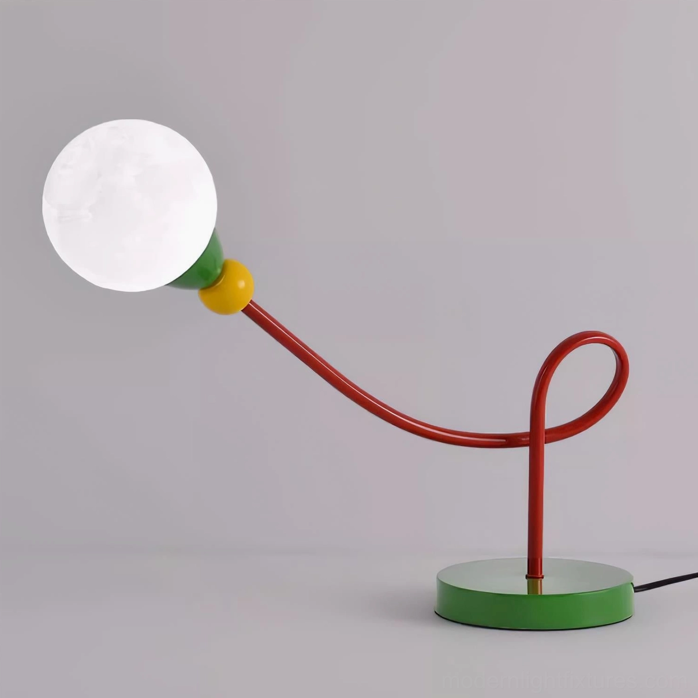 Loop arm sculptural lamp on wooden study desk with cactus decoration and book collection