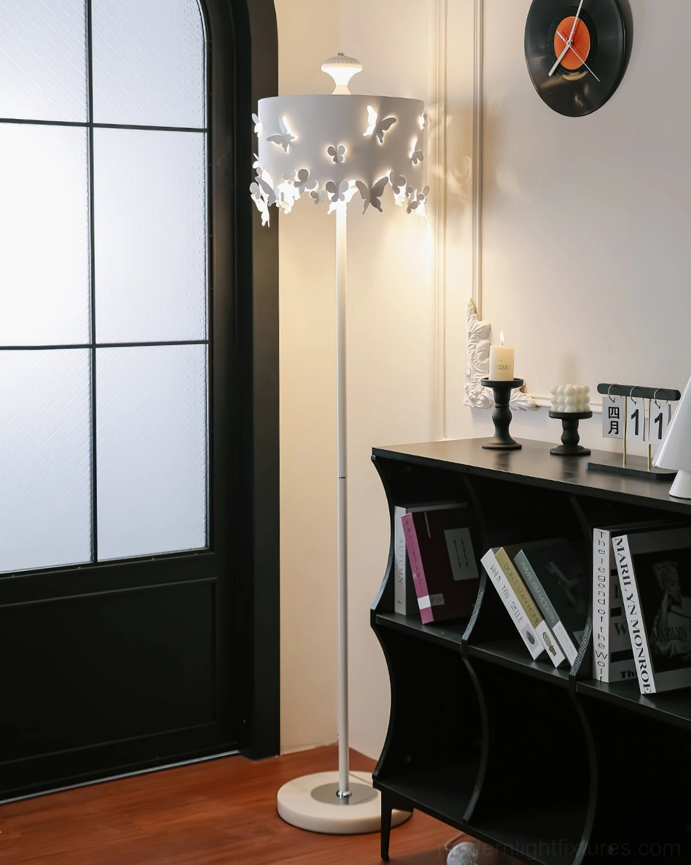 White metal butterfly floor lamp with cylindrical hollow-out shade, side three-quarter view in home display setting
