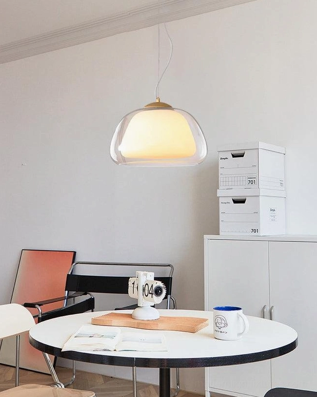 Contemporary jelly glass pendant light in minimalist dining space with round table and storage cabinets