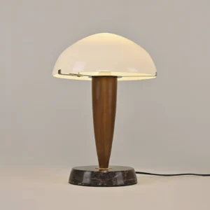 Contemporary marble base table lamp featuring walnut wood stem and dome shade with visible power cord on light gray backdrop