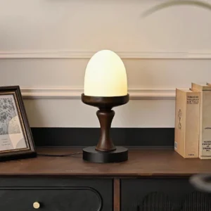 Lit contemporary organic table lamp on vintage wooden sideboard with books and framed art, three-quarter view