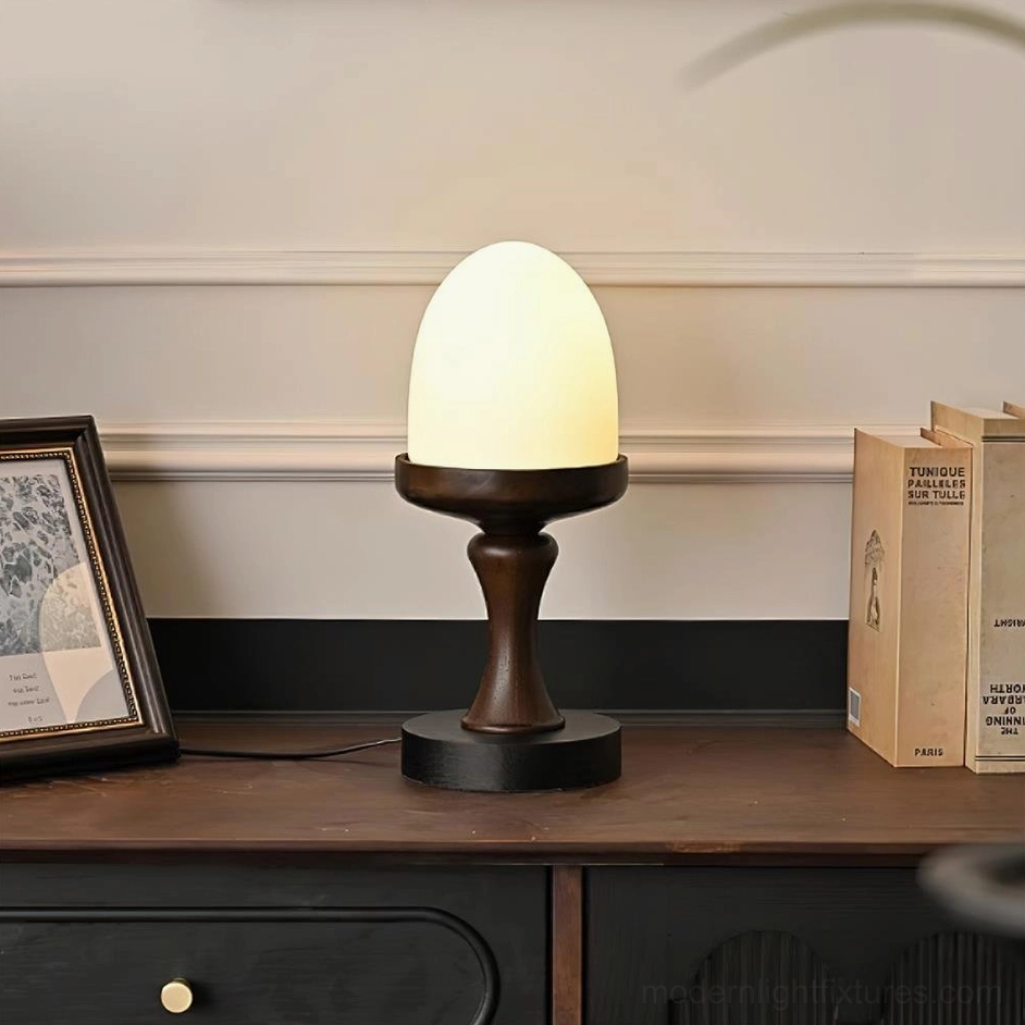 Lit contemporary organic table lamp on vintage wooden sideboard with books and framed art, three-quarter view