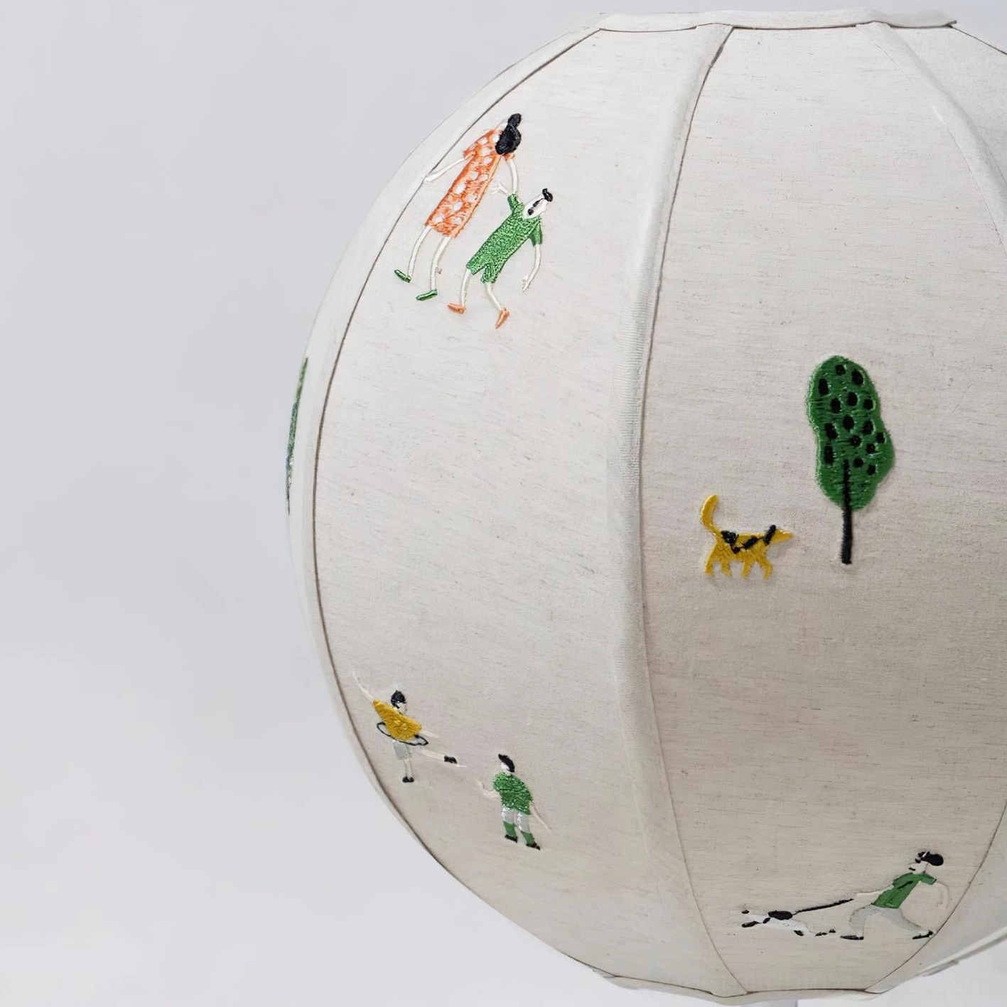 Modern embroidered fabric table lamp with chrome base and white linen shade featuring decorative storytelling motifs