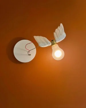 Modern feathered wall lamp mounted on terracotta wall with warm glowing light, single bulb configuration