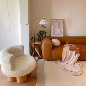 Modern pleated floor lamp in living room interior setting with tan sofa and brass finished metal frame beside side table