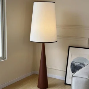 Contemporary wooden floor lamp with dark brown tapered base and illuminated fabric shade in modern living room with wainscot walls