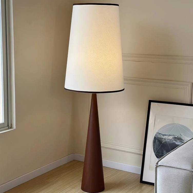 Contemporary wooden floor lamp with dark brown tapered base and illuminated fabric shade in modern living room with wainscot walls