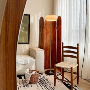 Contemporary floor lamp with warm glowing taupe shade and black marble base in retro living room setting - side angle view