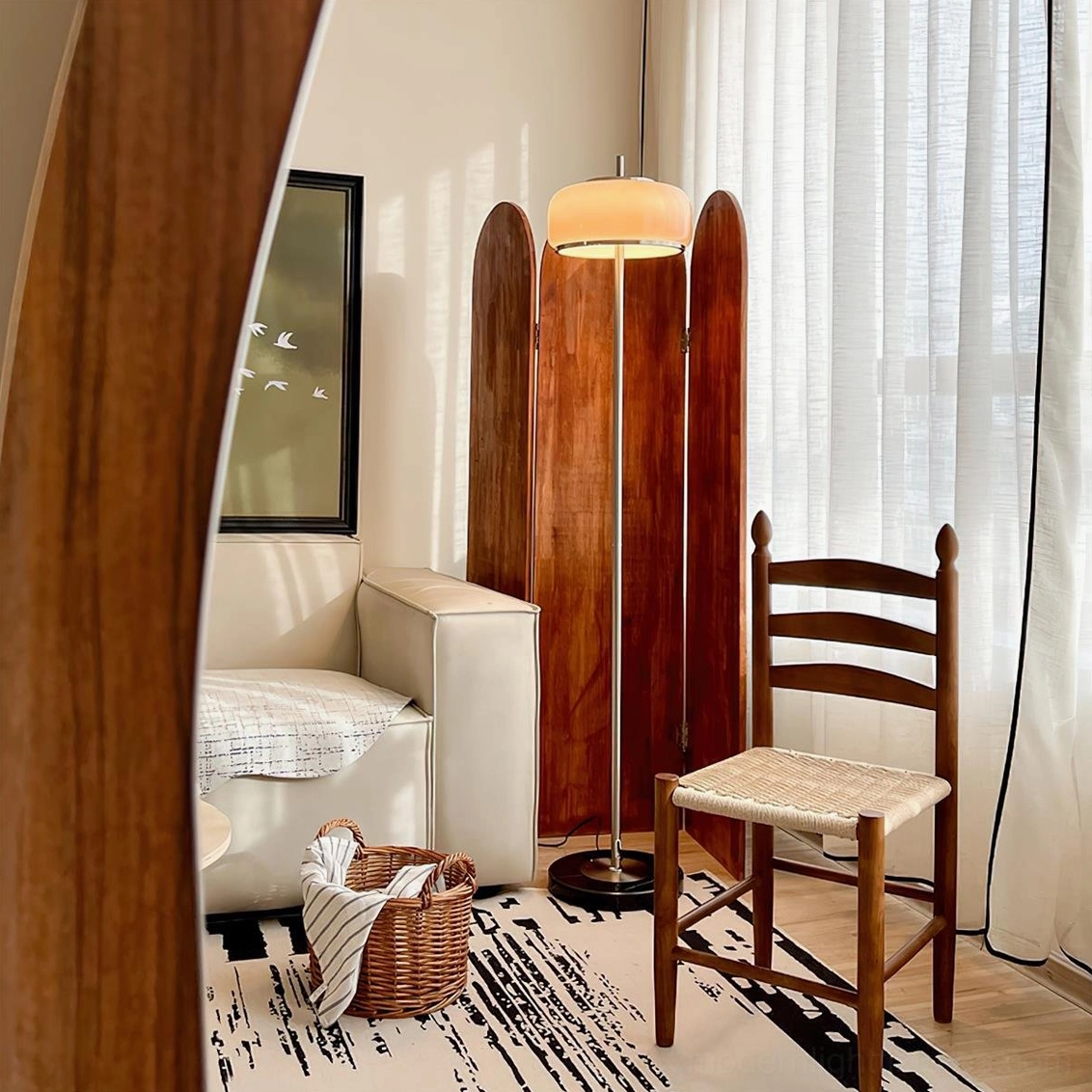 Contemporary floor lamp with warm glowing taupe shade and black marble base in retro living room setting - side angle view