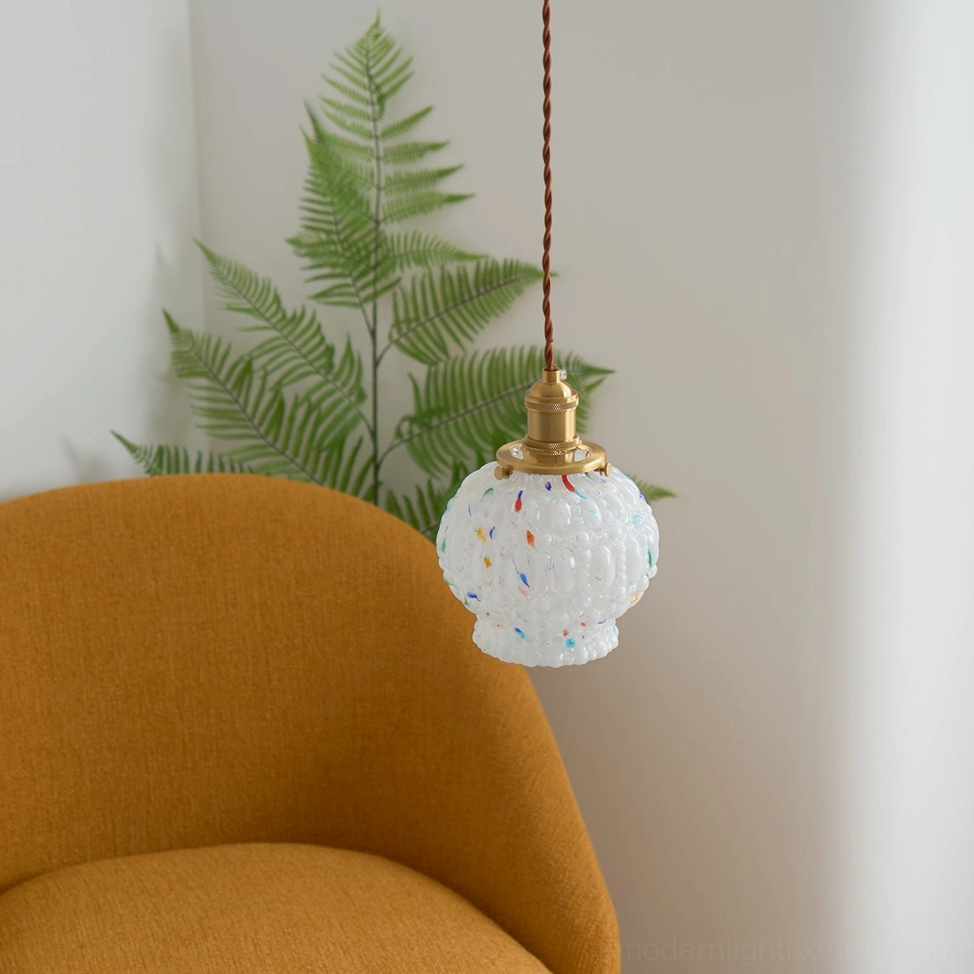 Modern frosted glass pendant light with colorful speckles scattered throughout shade, minimalist brass suspension design