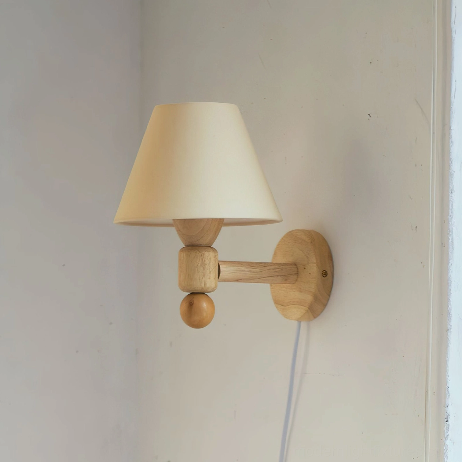 Modern geometric wall sconce with cream beige fabric shade and sculptural natural wood arm in warm tones