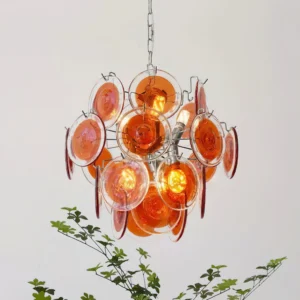 Modern glass disc pendant light fixture illuminated with warm glow and green plant decor