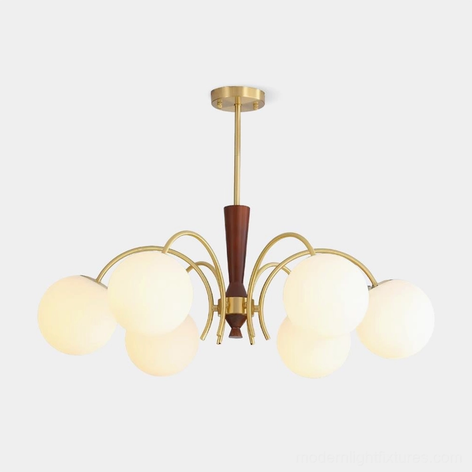 Modern 8-head globe chandelier with brass frame and frosted milk glass shades, front view against studio backdrop