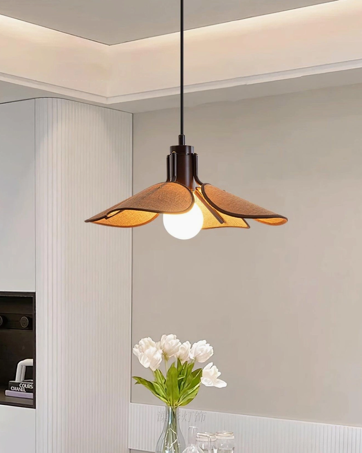 Modern hand-woven rattan pendant with dark suspension cord in contemporary kitchen dining space