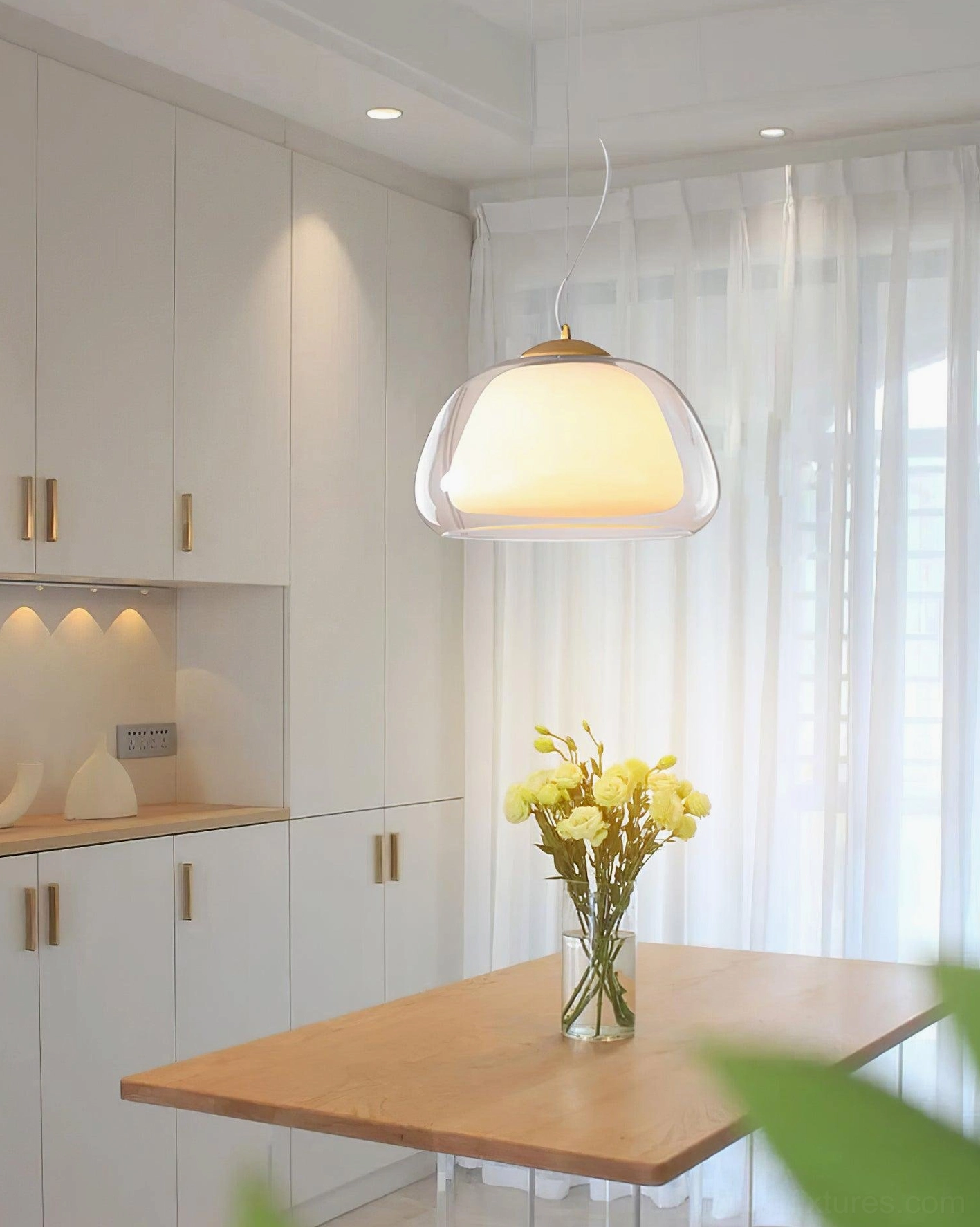 Contemporary glass dome pendant light in bright kitchen-dining area with white cabinets and botanical table décor