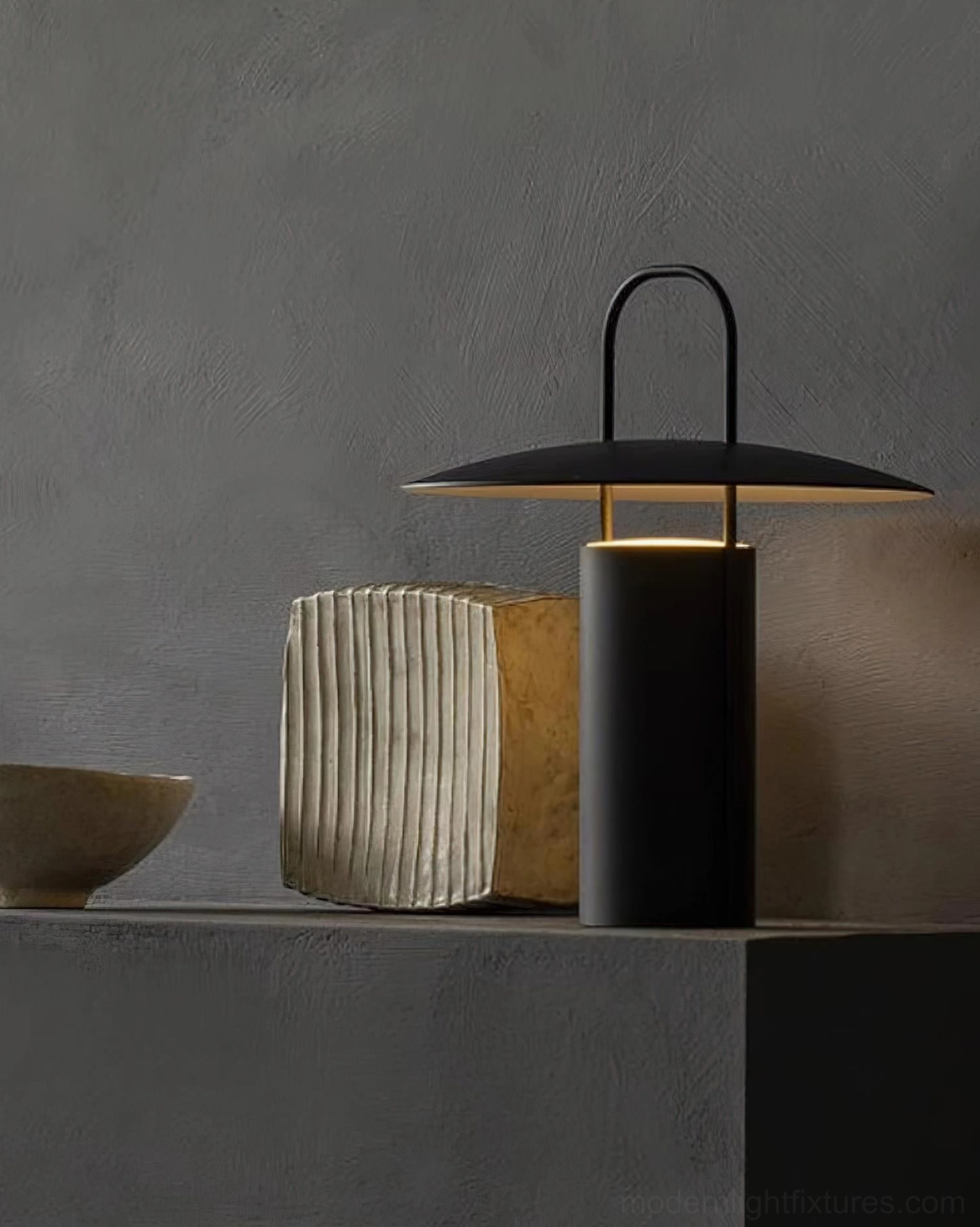 Contemporary black portable LED lamp with warm glow displayed on shelf with ribbed ceramic accessories