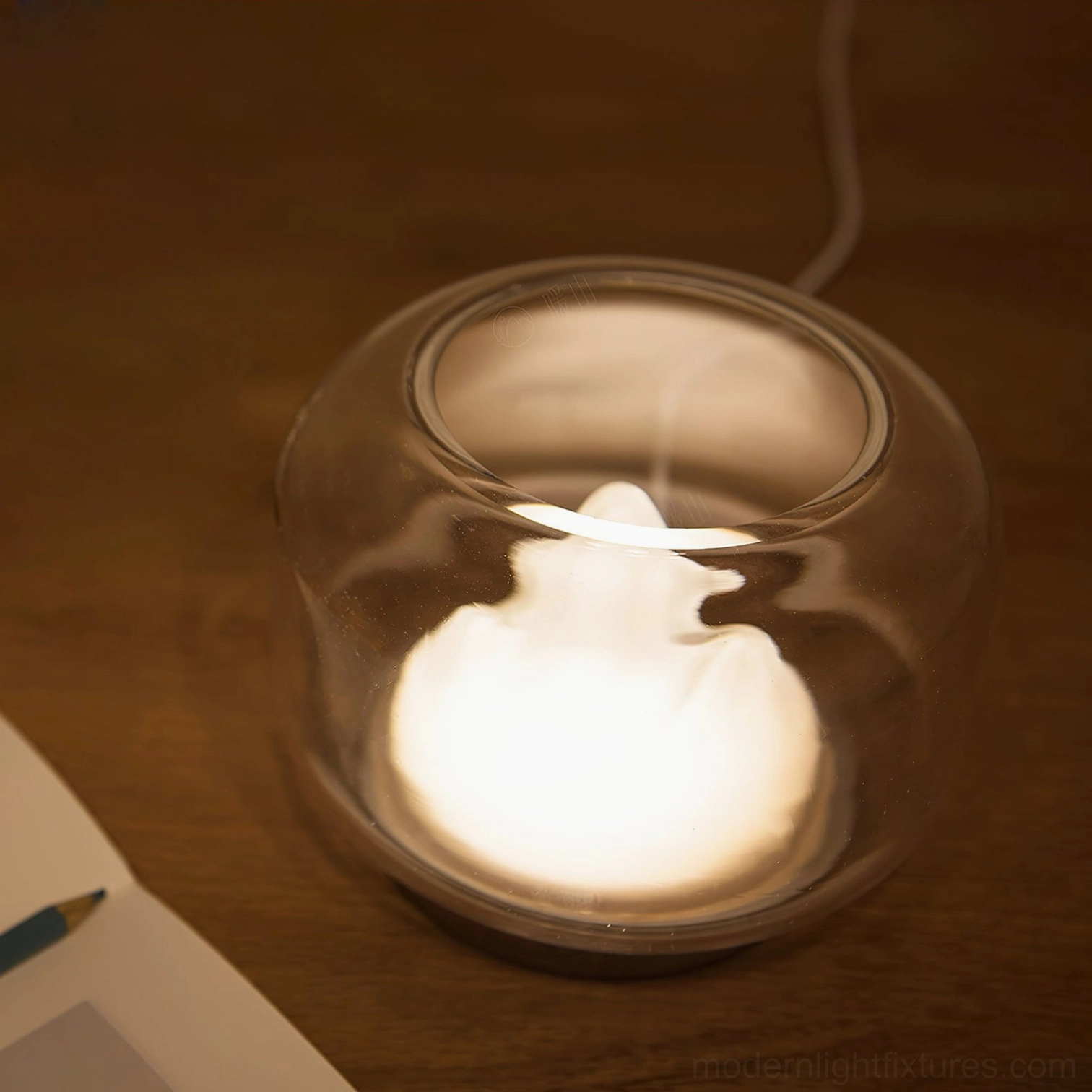Modern mountain lamp top-down close-up, clear glass dome with illuminated mountain light source and power cord