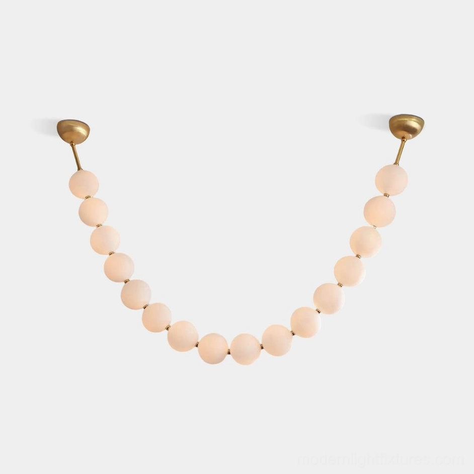 Modern pearl string chandelier with frosted acrylic spheres and brass hardware in U-shaped configuration