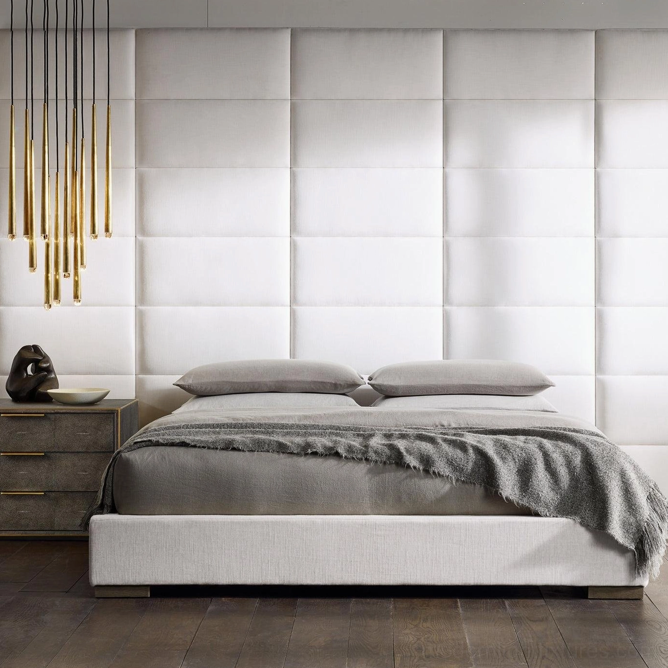 Minimalist brass cluster light fixture in modern bedroom with tufted headboard
