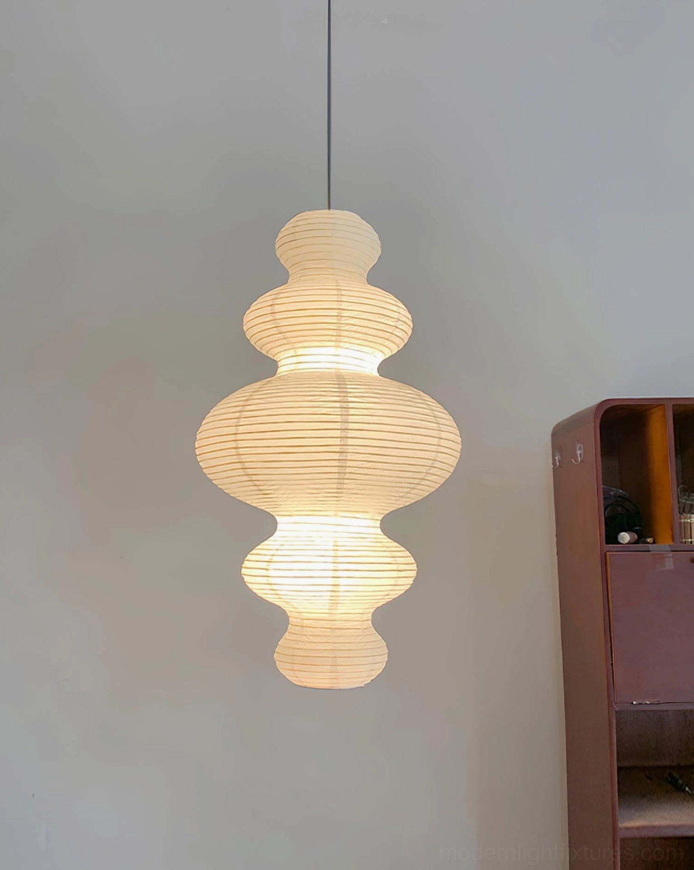 Hand-crafted white pendant light hanging above wooden cabinet in minimalist japandi interior design