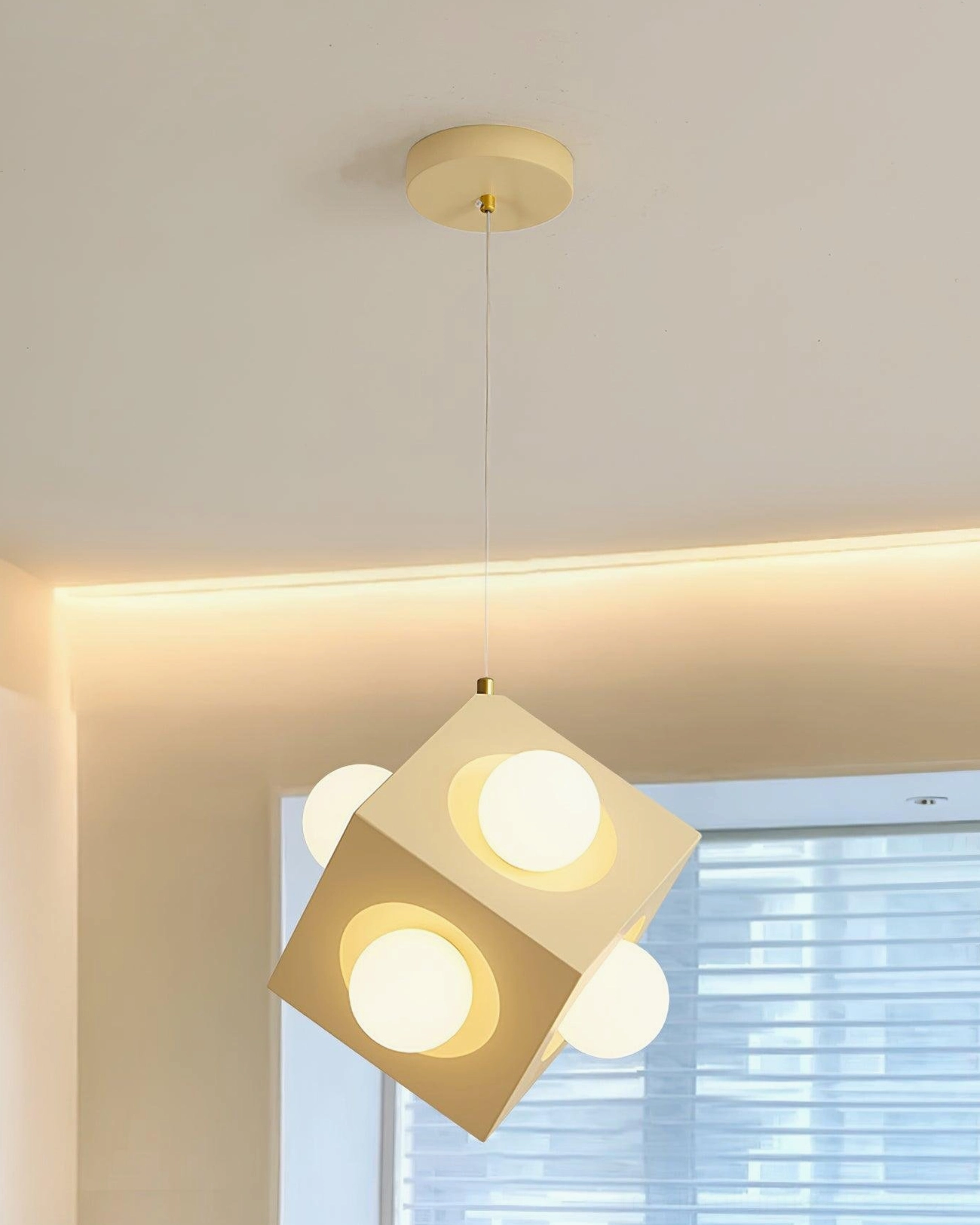 Geometric yellow pendant fixture installed at low angle in bright living space with warm glow and gold canopy