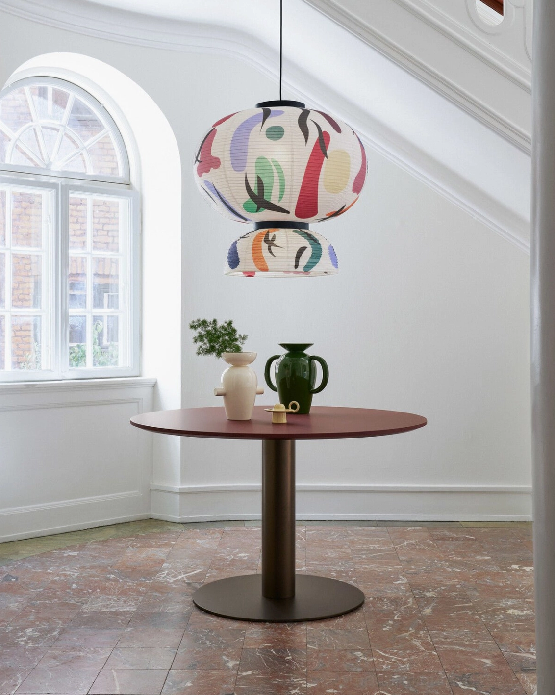 Modern decorative pendant light fixture suspended above round wooden dining table in contemporary home interior with warm ambiance
