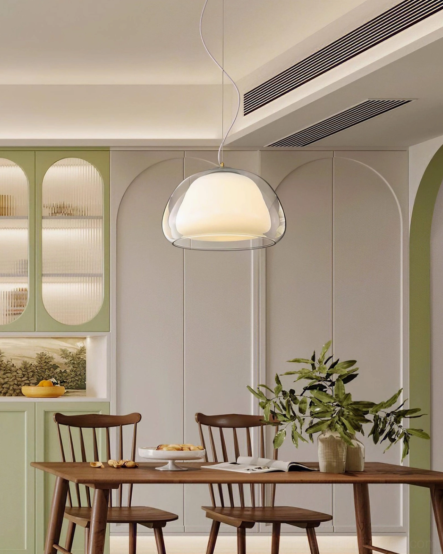 Warm glowing jelly glass pendant light in green-toned modern dining room above wooden dining table