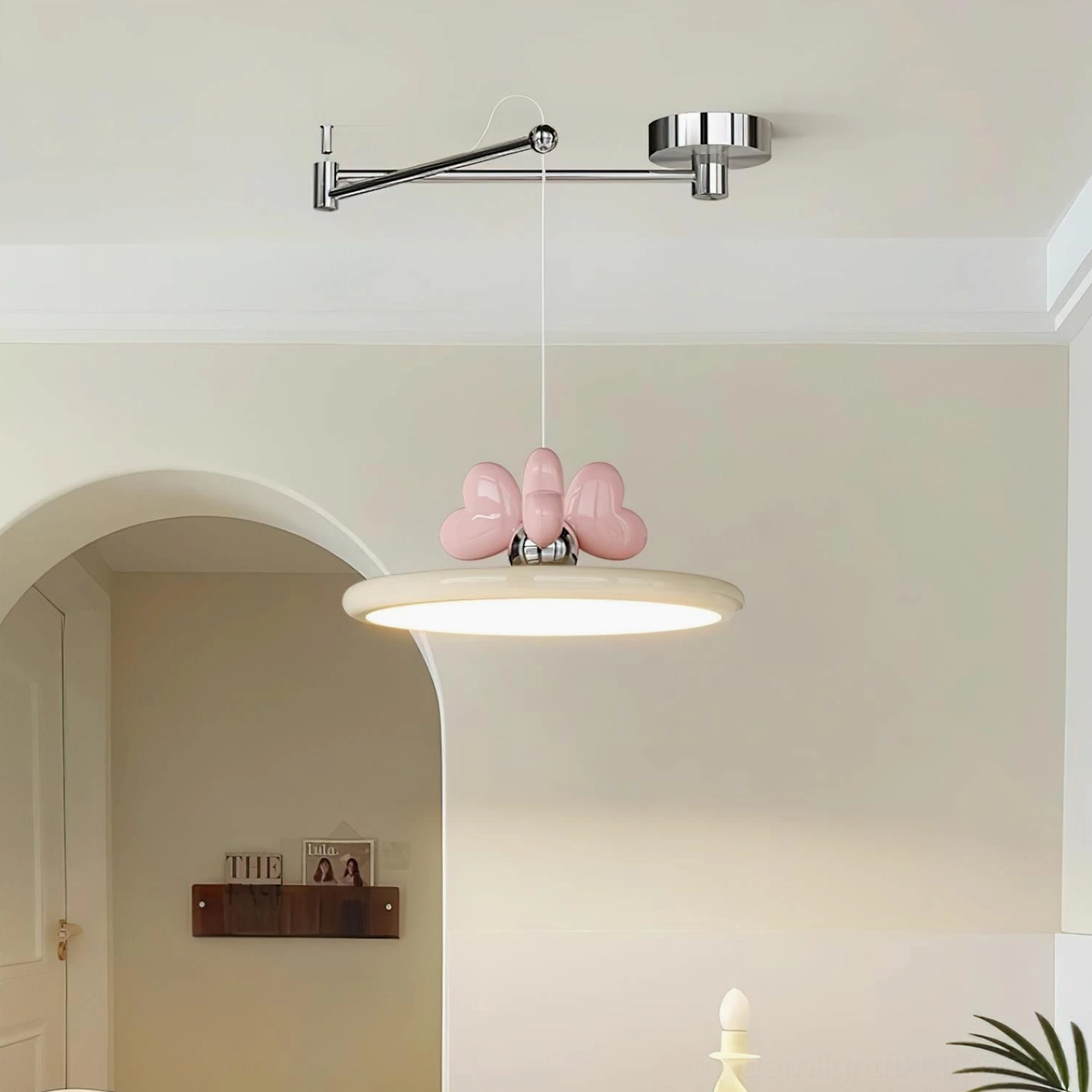 Contemporary pendant lamp installed in creamy residential entryway with pink heart bow decoration on beige shade