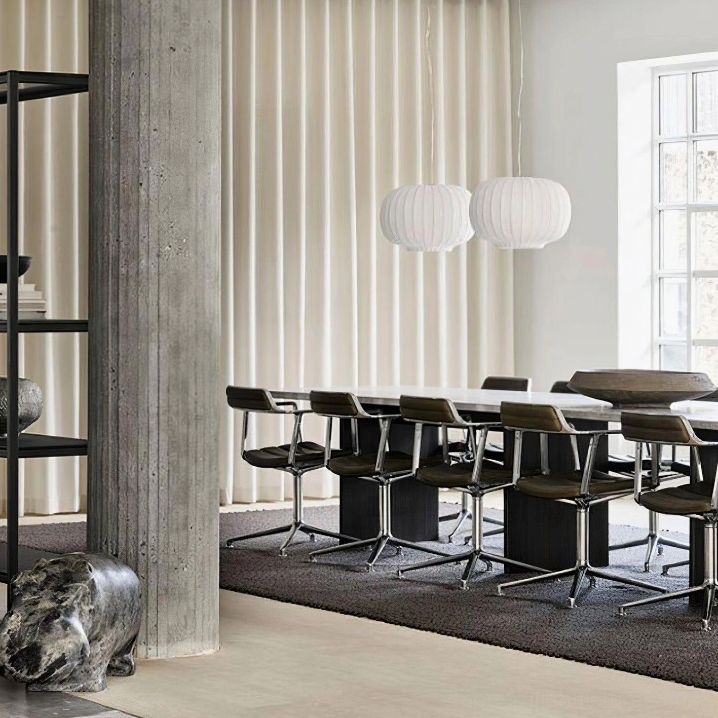 Pair of white ribbed fabric pendant lights hanging in contemporary dining room with concrete decor