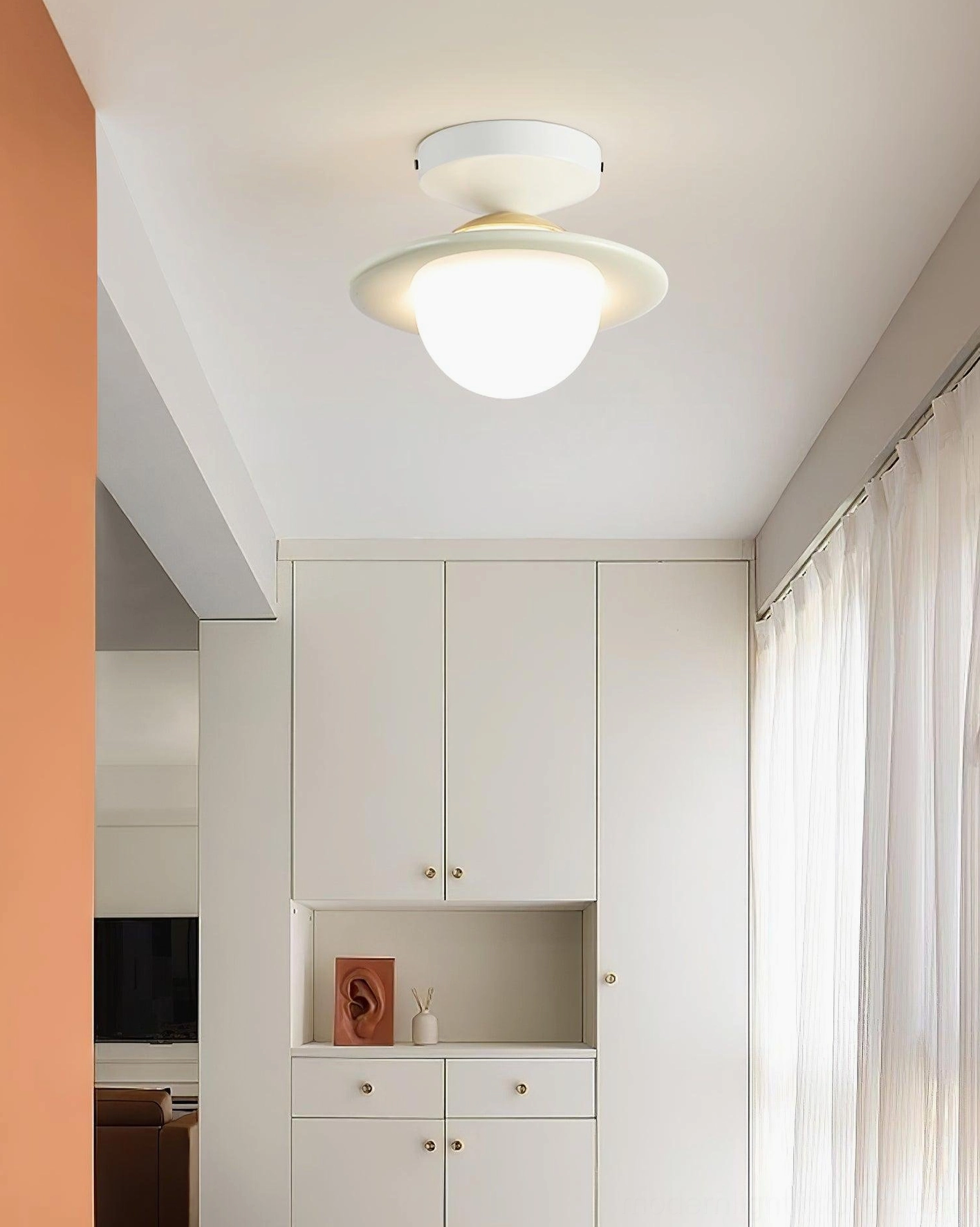 White planet flush mount ceiling fixture in modern hallway with built-in white cabinetry and minimalist décor