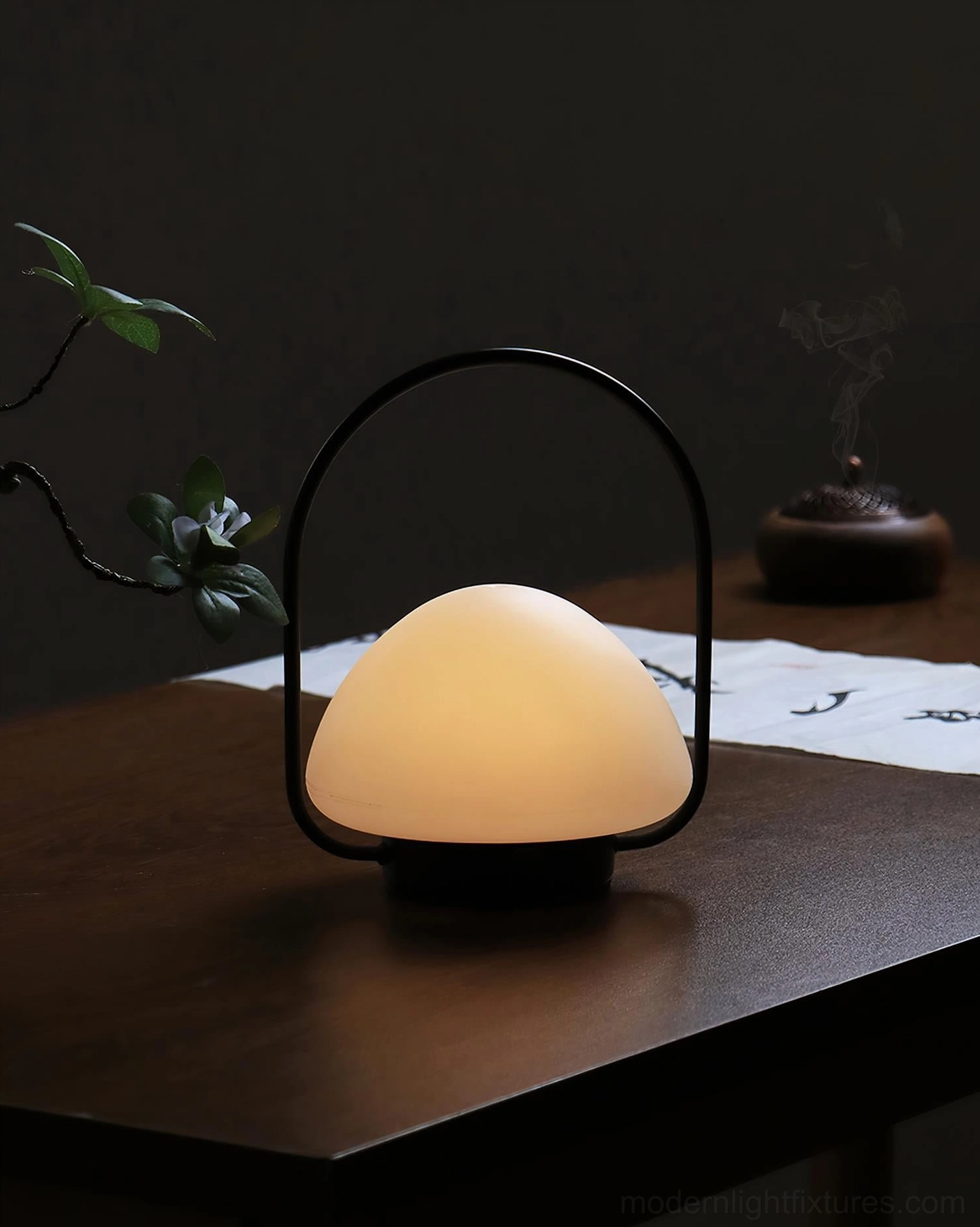 Modern portable table lamp on dark wood decorative desk, warm glowing frosted shade, interior design styling