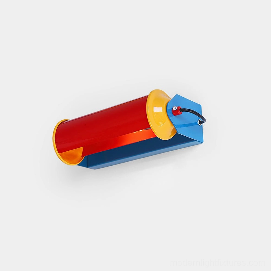 Modern rainbow arc wall sconce with tri-color cylindrical design in blue, red, and yellow, shown from left oblique angle in studio